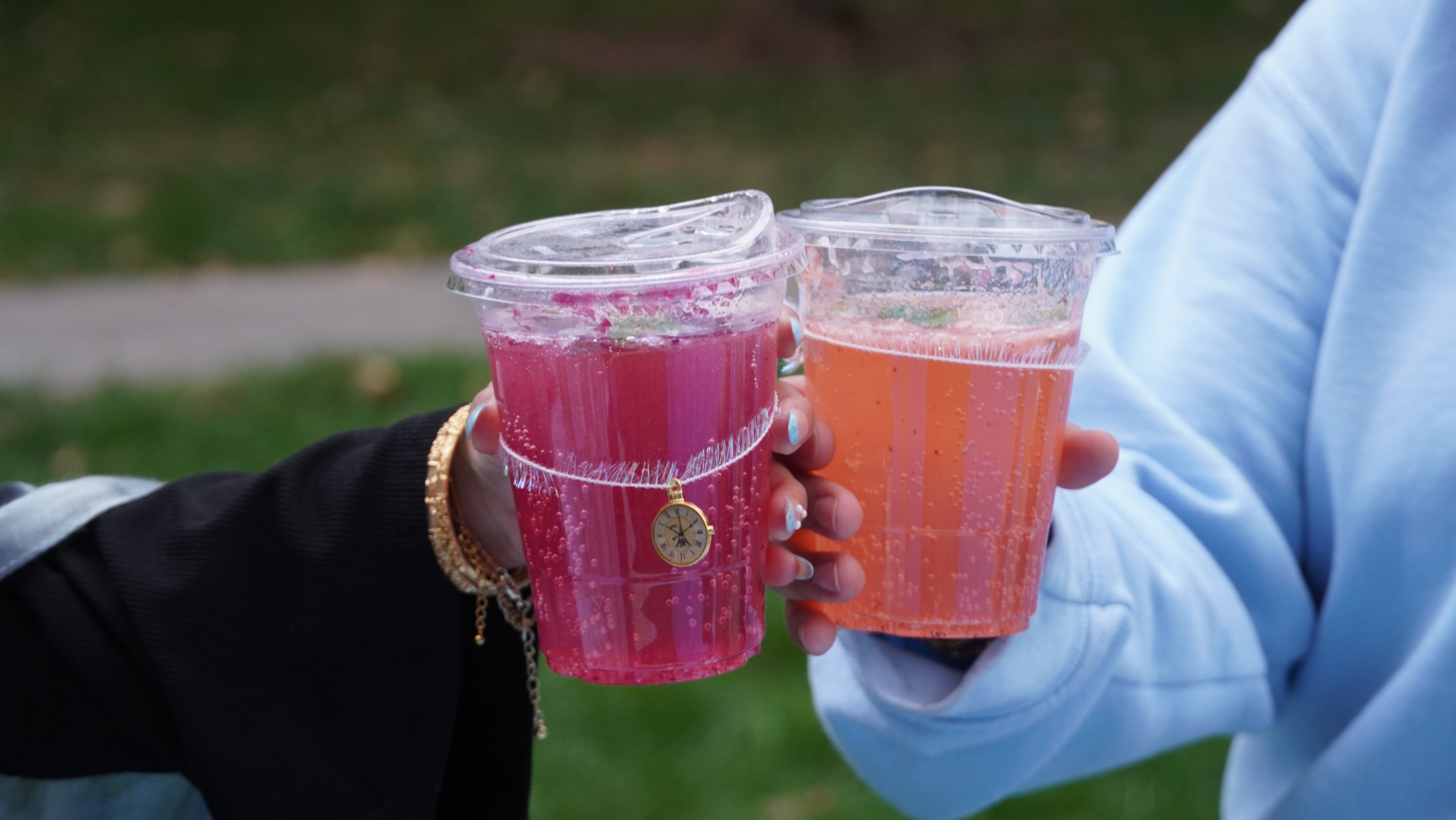 Two hands holding colorful sparkling drinks in toast